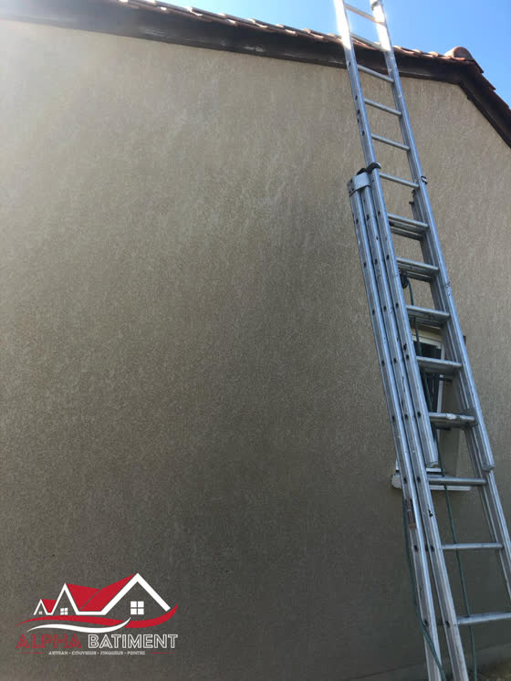 Échelle installée contre une façade enduite